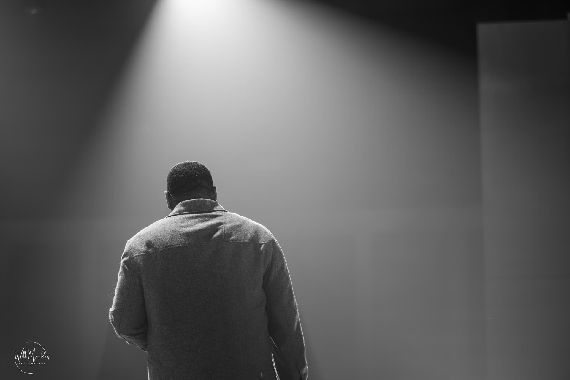 EJ LaTouche onstage beneath a spotlight in black and white